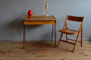 Avec ses fins pieds tubulaires, ses lignes modernistes et son plateau en formica voici un pupitre parfaitement typé de la décennie 1950 1960. Idéal pour un accompagner un enfant dans ses moments studieux ou créatifs, le bureau et la chaises forment un ensemble aussi cohérent que pratique.