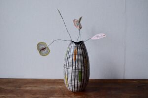 Joli trait décoratif minimaliste pour ce joli vase midcentury! Il est orné de taches de couleur abstraites mises en relief par un email texturé et rayé de lignes noires. Très sobre, c'est une belle pièce déco vintage.