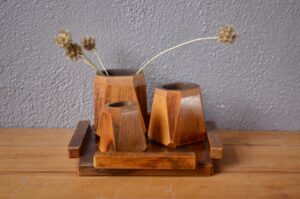 Dans un style Art Déco, ce set de bureau fait honneur au travail du bois. Trois vases de bois aux formes sobres et minimales accompagnent un plateau carré. Purement décoratif ou usuel comme set de bureau ce bel ensemble se distingue par sont élégance retenue.