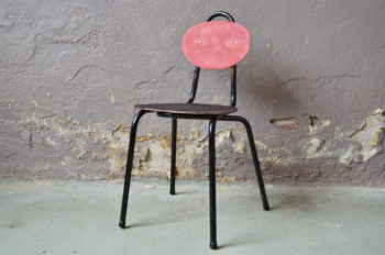 Voilà une chaise enfant facétieuse et ludique prête à être embarquée dans tous les bricolage et activités. Réalisée en tubes d'acier coudés et laqués et de noir c'est une chaise vintage qui datent certainement des années 60. Nous aimons l'association de couleur tonic et l'aspect texturé de la peinture rouge et noire de l'assise et du dossier. Son design est traité de façon  ludique et dynamique avec des formes géographiques géométriques simples. Associée un petit bureau vintage elle sera un compagnon parfait pour le travail ou les bricolages mais elle pourra également servir d'assise pour le jeu ou de table de nuit originale.