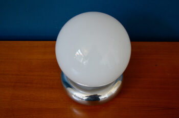 Comme une lune posée sur un anneau de métal, cette jolie lampe est une production italienne des années 70. Une large sphere de verre opalescent est disposée sur une pièce de métal chromé. L'ensemble est très graphique, sobre élégant et diffuse une douce lumière dans toutes les directions. Parfaite lampe d'ambiance, elle se mettra en valeur et apportera sa touche spatiale à la déco intérieure.