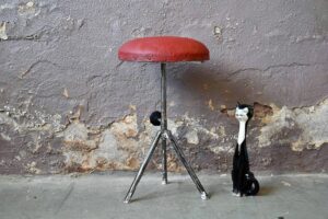 Compact, astucieux, reglable et délicieusement patiné, ce petit tabouret est un concentré de vintage. Sa structure légère et minimale est en acier tubulaire, elle porte une assise garnie et tapissées de vinyle rouge.