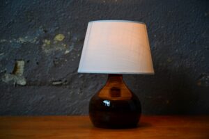 Cette belle lampe propose un design brut, tout en retenue. Le pied en céramique tourbée de forme sphérique, au col légèrement allongé, est en grès, à l'aspect brillant et nuancé. Dans un esprit campagne chic, sobre et wabi-sabi, ce luminaire apportera sa touche "terre" à une ambiance intérieure authentique et chaleureuse.