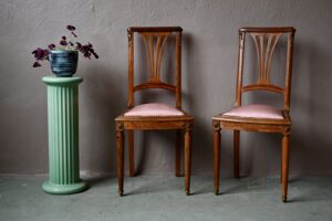 Cette paire de chaises en noyer, de style Louis XVI, s'exprimeront parfaitement dans une décoration sophistiquée et classique. Les dossiers forment une lyre ajourées, des éléments de bronze viennent agrémenter le tout. L'assise est tapissée de satin rose à l'aspect brillant. Ces chaises anciennes sont prêtes à s'intégrer dans un intérieur raffiné.