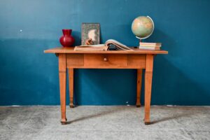 De dimensions compactes, d'allure authentique et rustique cette belle table ancienne à tiroir possède un lustre et une patine offerte par une vie bien remplie. Tout en bois massif, elle pratique et pourra être utilisée dans une cuisine, comme bureau ou en table d'appoint. Nous aimons la chaleur et le veinage du bois ainsi que ses pieds élancés et finement ornementés.